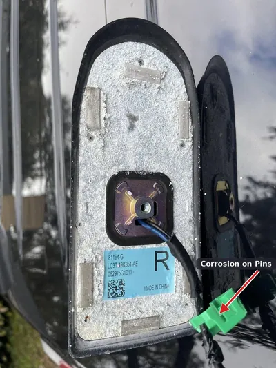 Close-up of the underside of a used roof antenna base showing green and white corrosion on the electrical pins.