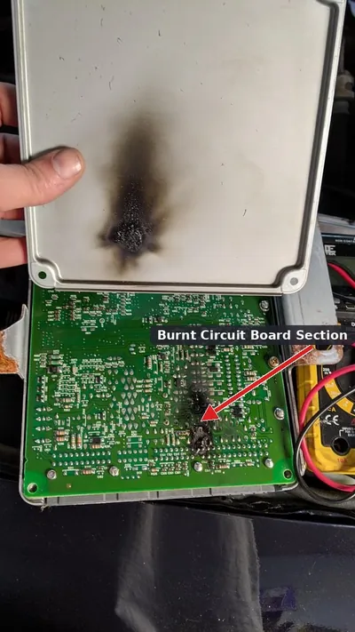 An opened engine control module revealing a burnt circuit board, illustrating internal failure.