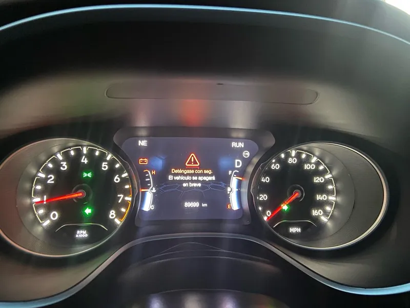 Illuminated check engine light on the dashboard instrument cluster of a Jeep Compass.