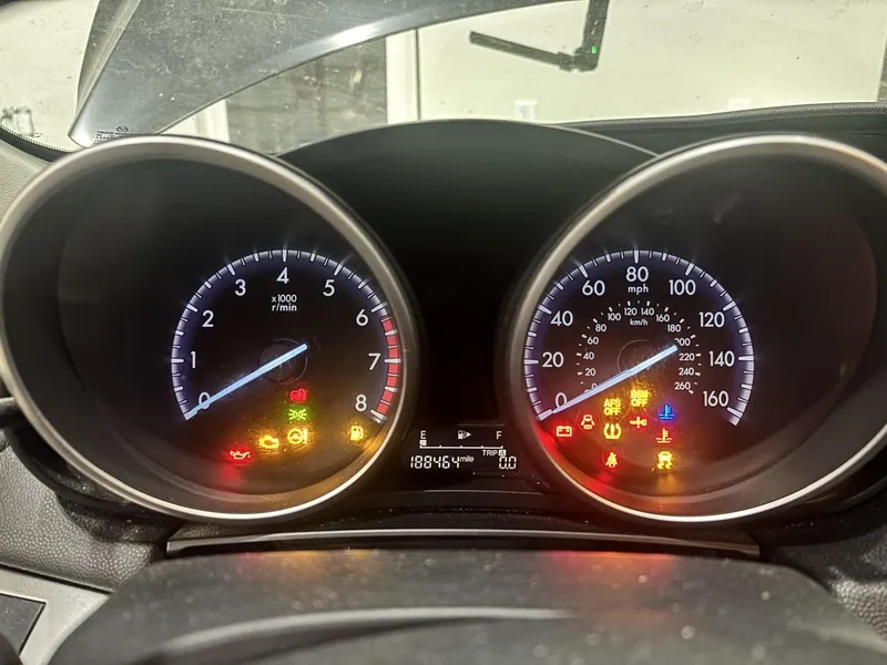 A 2012-2013 Mazda 3 instrument cluster illuminated with multiple warning lights.