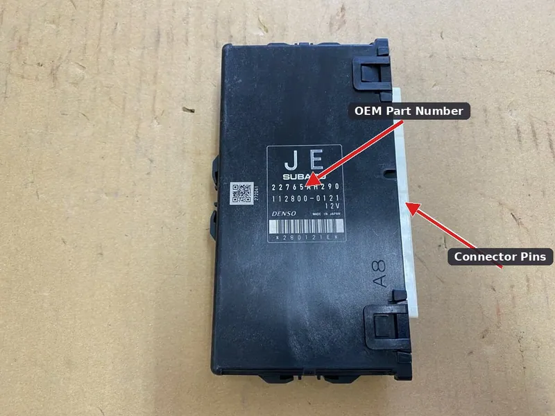 A used OEM Engine Control Module for a Subaru Forester, showing the manufacturer part number label and electrical connector pins.