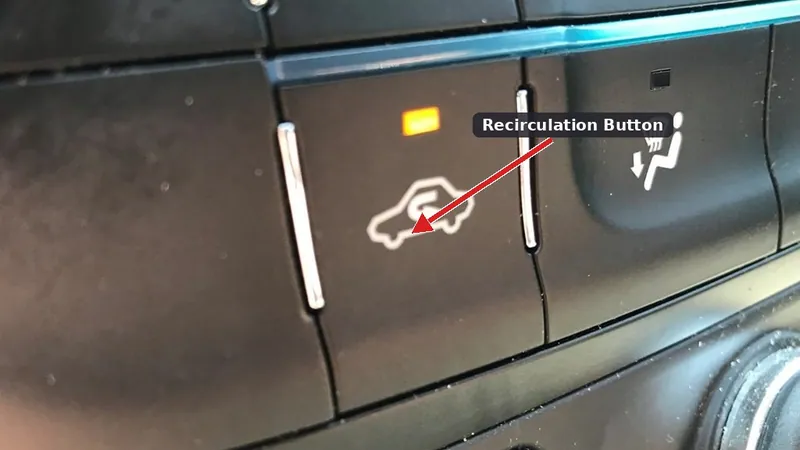A car's climate control panel showing the recirculation button, which features an icon of a car with a U-turn arrow inside.