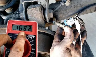 A mechanic using a digital multimeter to test the electrical resistance and voltage at the wheel speed sensor connector.