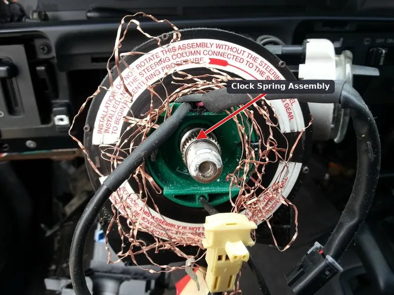 A steering column with the steering wheel removed, exposing the clock spring and steering angle sensor assembly.