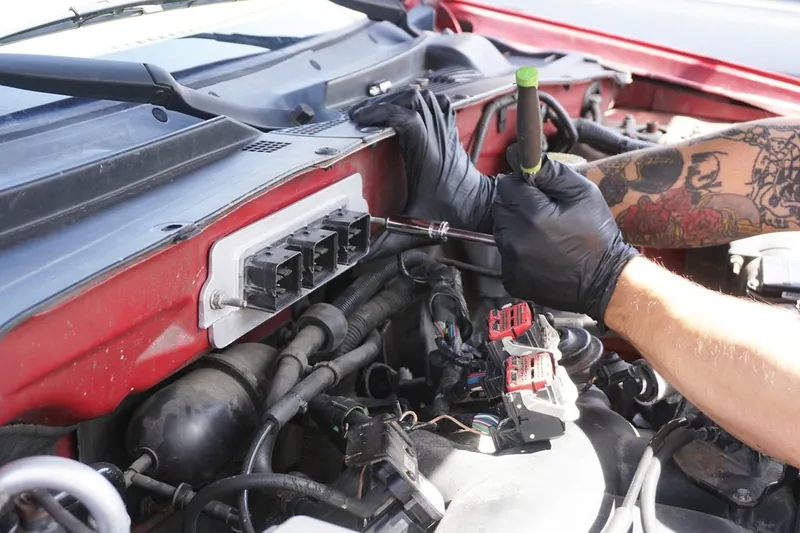 A mechanic installing or programming a new Engine Control Module (ECM) in a vehicle.