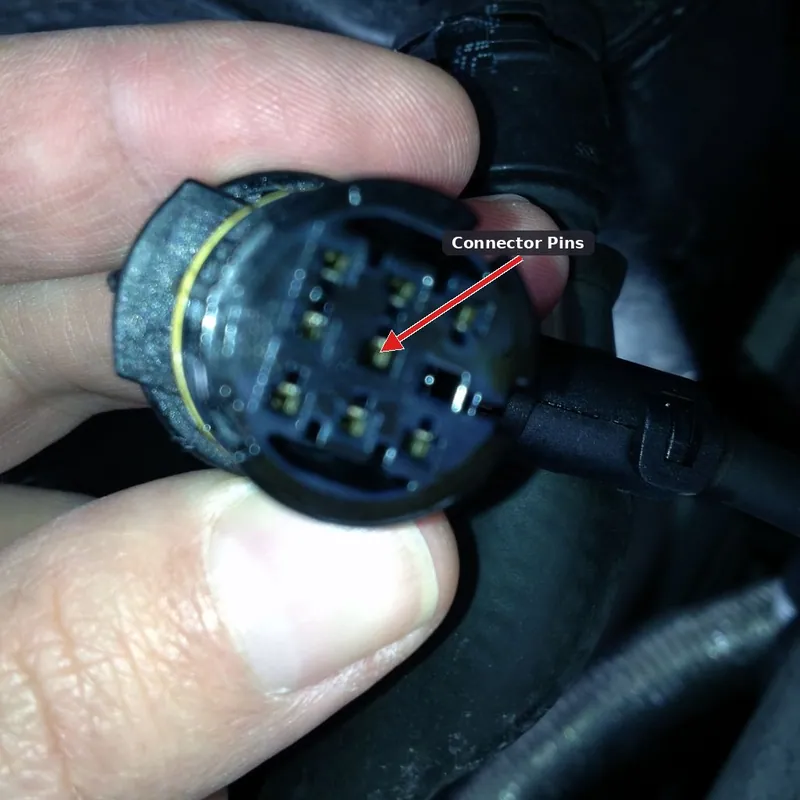 A mechanic inspecting an engine sensor connector for oil contamination or using a scan tool to monitor live fuel pressure data.
