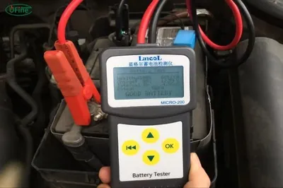 Mechanic performing a professional load test on a 12V car battery using a digital tester.