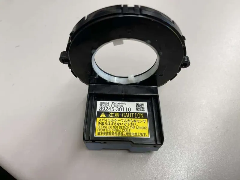 A steering angle sensor and clockspring assembly removed from a vehicle's steering column.