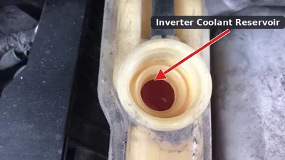 The inverter coolant reservoir and electric water pump located in the engine bay of a 2nd generation Toyota Prius.