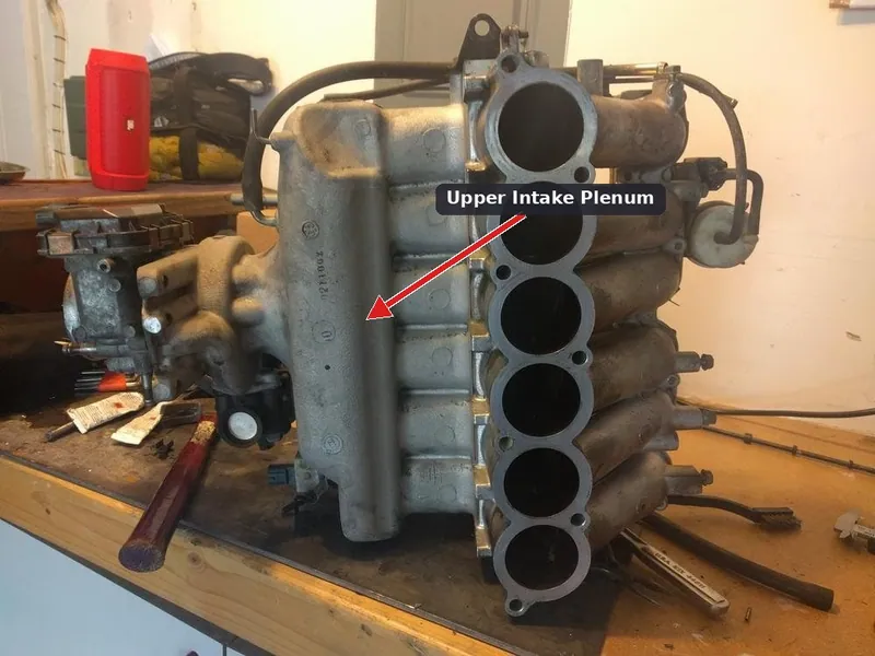 The upper intake plenum on a Mitsubishi 3.8L V6 engine which must be removed to reach the rear spark plugs.