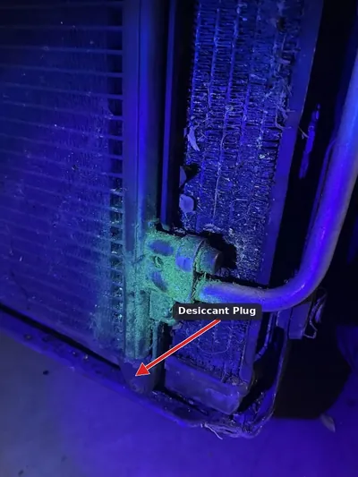 Close-up of a Chevrolet Equinox AC condenser showing the desiccant plug area where leaks commonly occur according to TSB 18-NA-162.