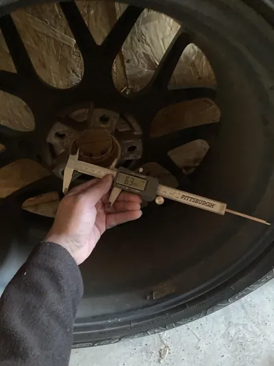 A person inspecting the inside barrel and bead seat of an unmounted alloy wheel.