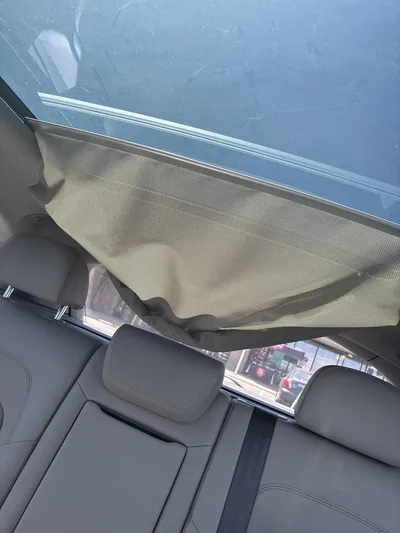 A torn and detached panoramic sunroof shade fabric hanging loosely from the interior headliner.